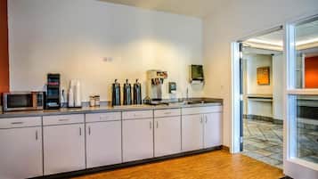 A kitchenette with a microwave, coffee maker, and espresso machine.