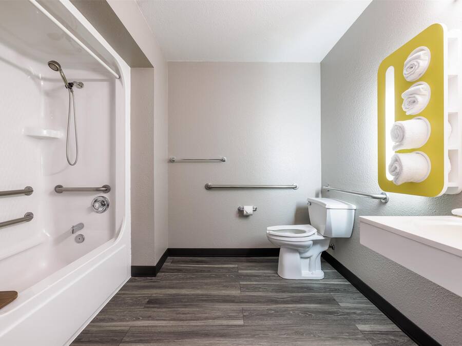 A modern bathroom with a bathtub, toilet, and a towel rack.