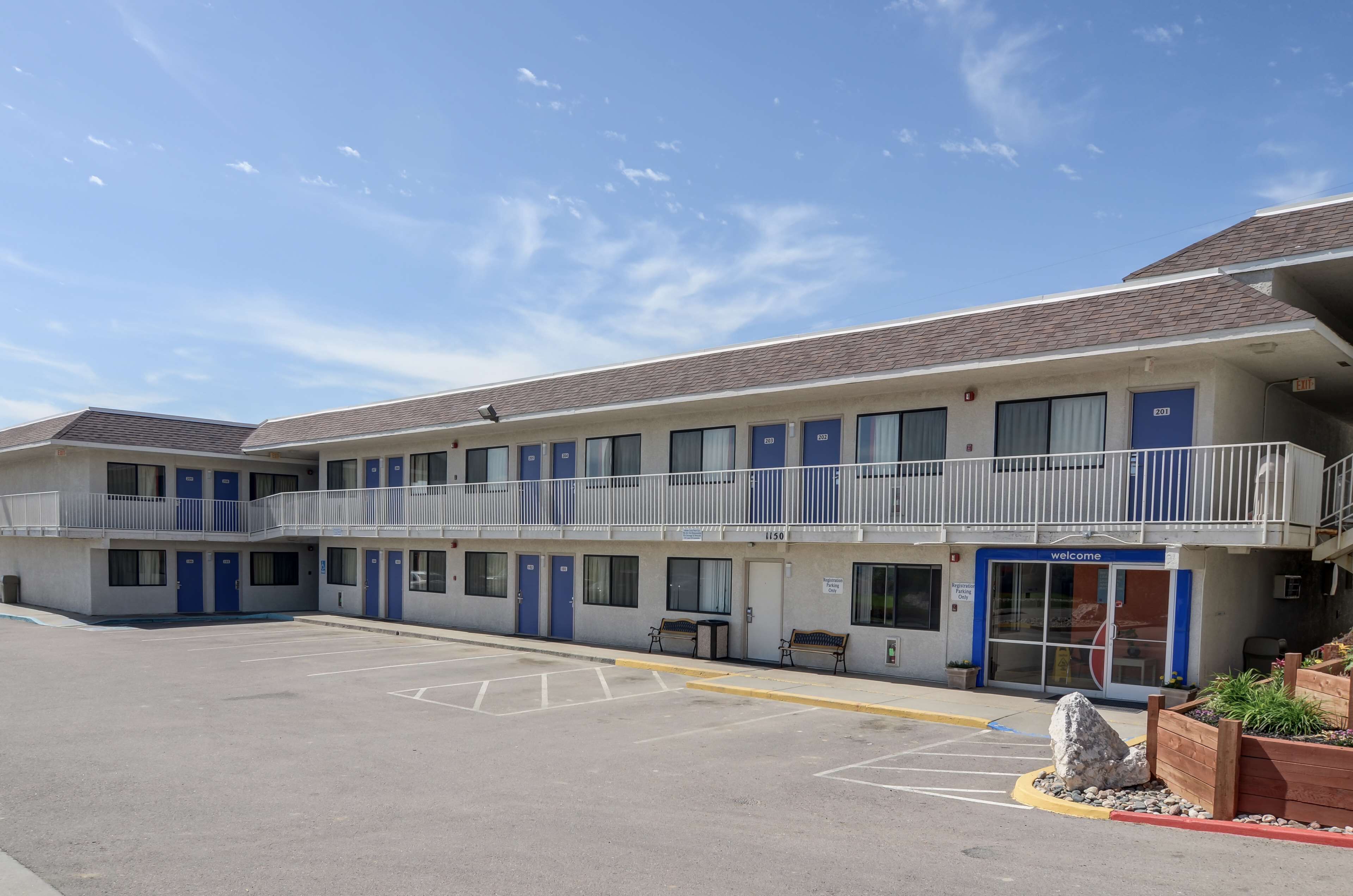 A motel with a central entrance, multiple rooms on each floor, and a parking lot.