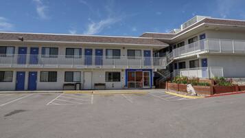 A motel with a parking lot, multiple rooms, and a balcony.