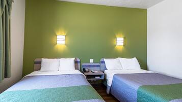 A hotel room with two beds, green walls, and two wall-mounted lights.