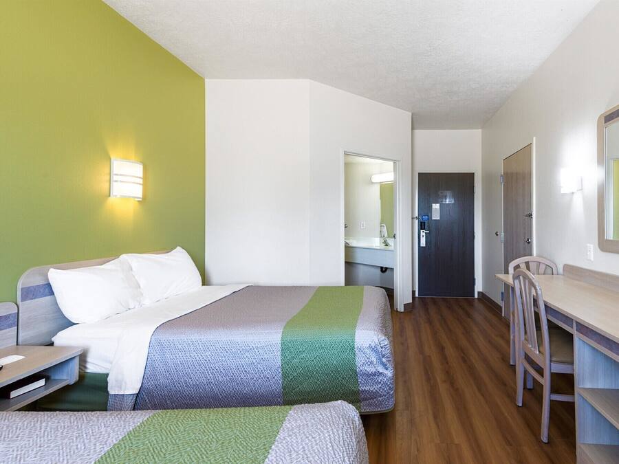Een hotelkamer met twee bedden, een bureau, een stoel en een spiegel.