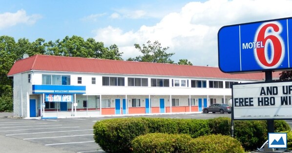 A motel with a red roof, white exterior, and a blue sign. It has a parking lot and a sign indicating free HBO. - Motel 6 Frackville, PA (Frackville)