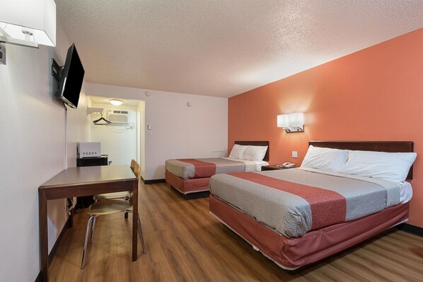 A hotel room with two beds, a desk, a chair, a TV, and a wall-mounted heater. - Motel 6 Frackville, PA (Frackville)