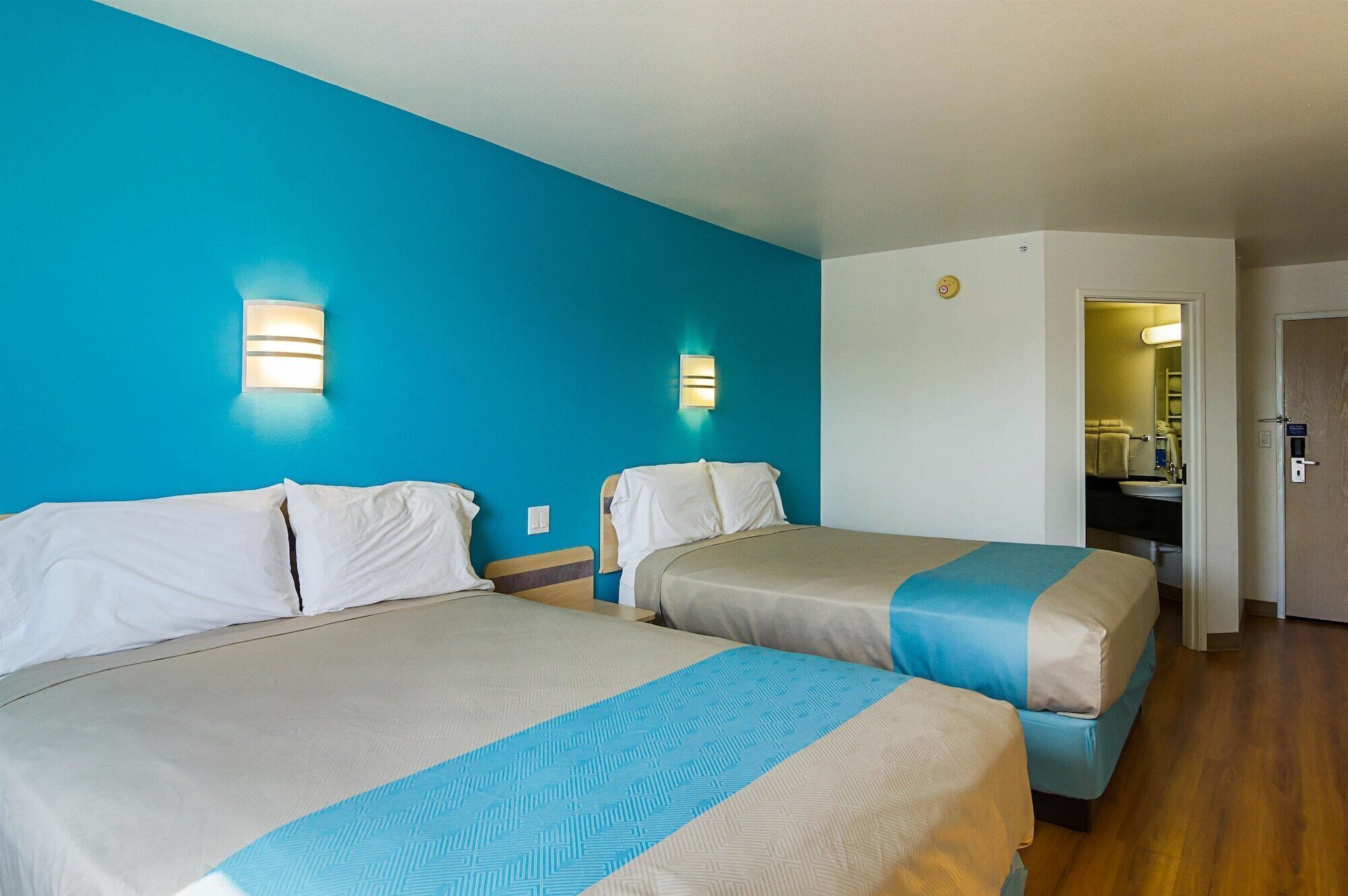 Una habitación de hotel con dos camas, un baño y un escritorio.