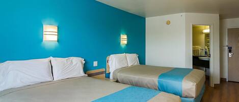 Una habitación de hotel con dos camas, un baño y un escritorio.