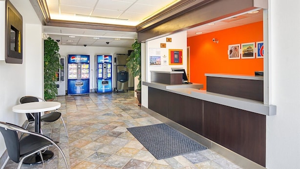 A hotel reception area with a modern design, including a reception desk, seating area, and vending machines. - Motel 6 Wheatland, WY (Wheatland)