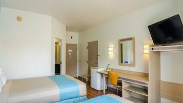 A hotel room with two beds, a desk, a chair, a television, and a mirror.