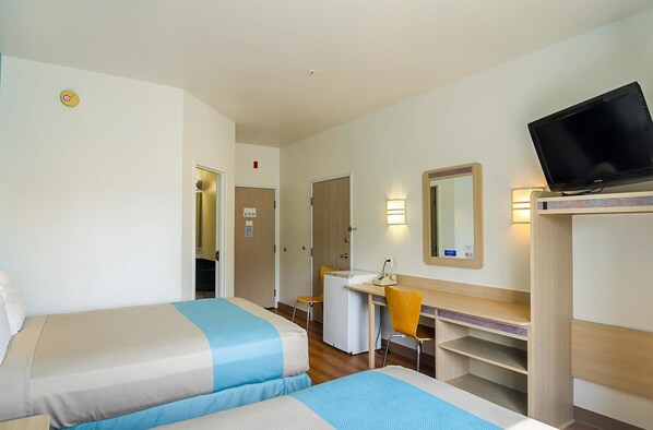 A hotel room with two beds, a desk, a chair, a television, and a mirror. - Motel 6 Wheatland, WY (Wheatland)