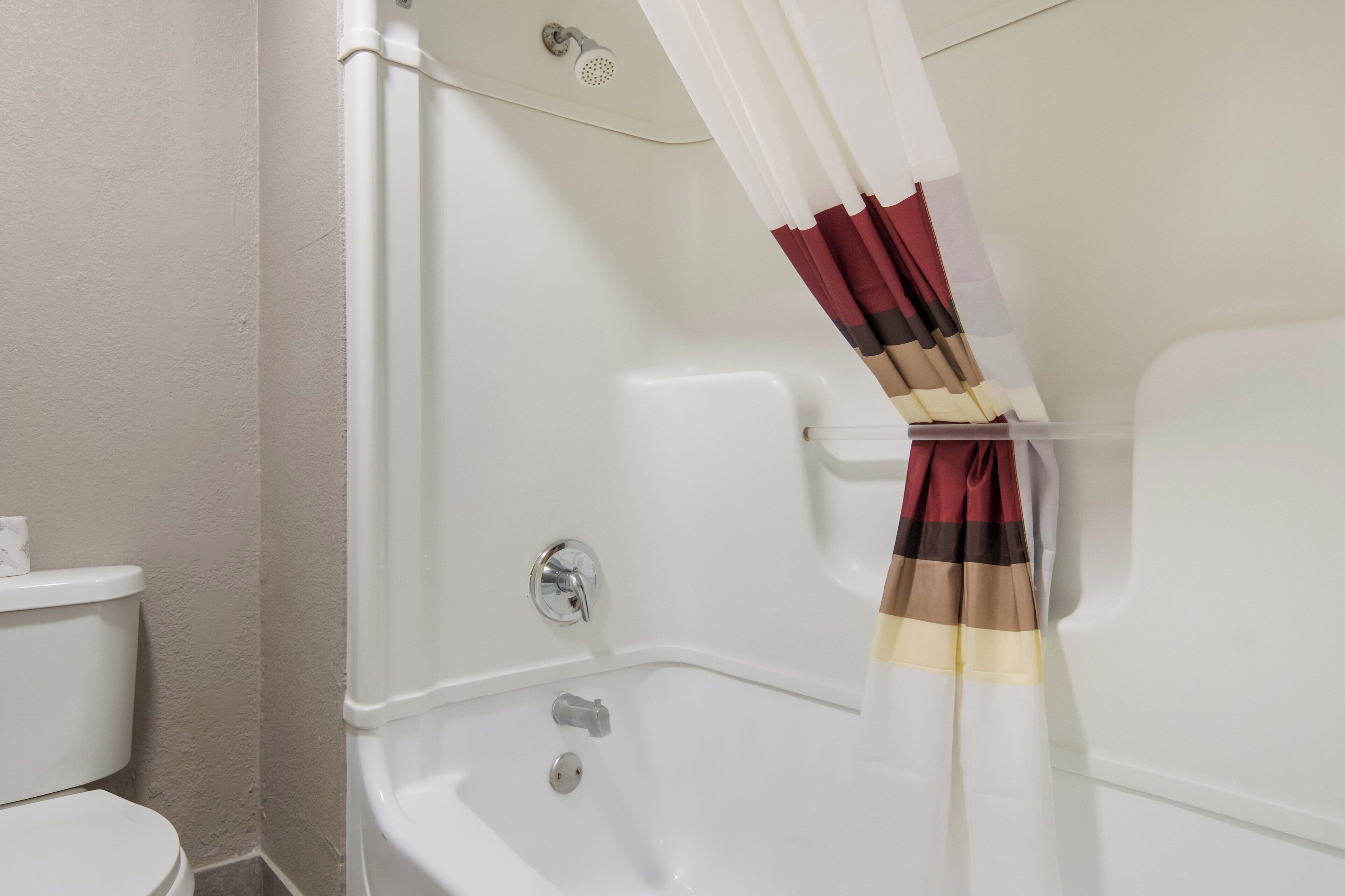 A bathroom with a bathtub, toilet, and a shower curtain.