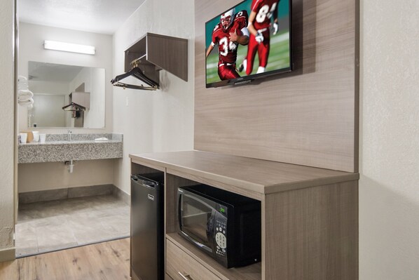A modern bathroom with a built-in microwave, a sink with a granite countertop, and a mirror above the sink. - Red Roof Inn Fort Worth South (Fort Worth)