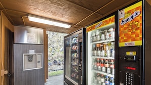 A vending machine area with Snapple and other beverage options, a refrigerator, and a door leading outside. - Motel 6 Gold Beach, OR (Gold Beach)