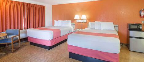 Une chambre d’hôtel avec deux lits, un bureau, une chaise, un four à micro-ondes et un réfrigérateur.