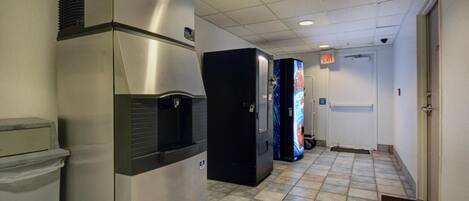 Un pasillo con dispensador de agua, refrigerador y máquinas expendedoras.