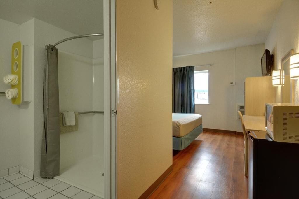 Een hotelkamer met douche, bed, bureau en televisie.
