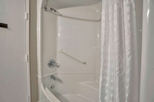 Una bañera blanca con cortina de ducha, barra de apoyo y grifo.