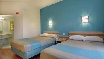 A hotel room with two beds, a bathroom, and a mirror.