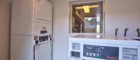 A laundry area with stacked dryers and a front-loading washing machine.