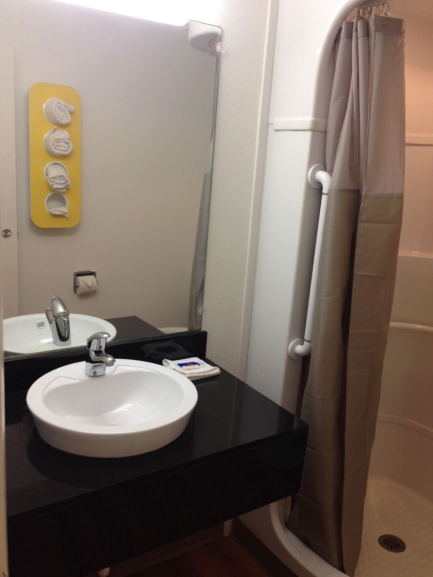 A bathroom with a white sink, a mirror, a towel rack, and a shower curtain.