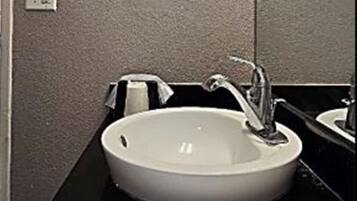 A bathroom with a white sink, a black countertop, and a towel on the counter.