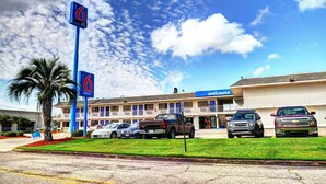 A motel with a '6 Enter' sign, a 'Welcome' sign, and a parking lot with several vehicles. - Motel 6 Slidell, LA - New Orleans (Slidell)