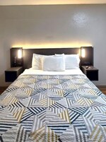 Una habitación de hotel con cama, dos mesitas de noche y una colcha estampada.