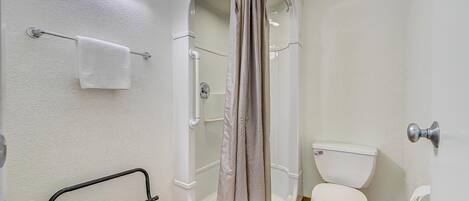 Un baño con cabina de ducha, inodoro y toallero.