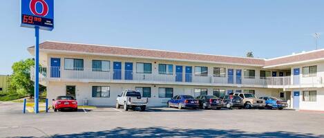 A motel with a '6' sign, multiple parking spaces, and a two-story building with balconies.