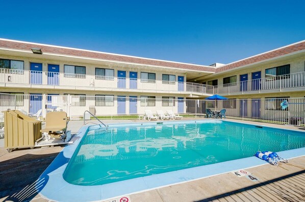 A hotel with a swimming pool, multiple balconies, and outdoor seating areas.