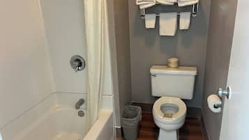 A bathroom with a bathtub, toilet, and a towel rack with folded towels.