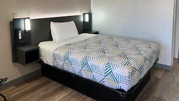 A hotel room with a bed, a nightstand, a phone, and a wall-mounted light.