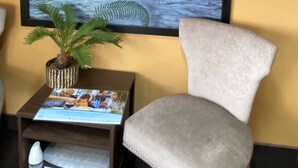 A framed picture of a person fishing on a river, a potted plant, and a small table with a magazine and a white object. - Super 8 by Wyndham Midwest City OK (Midwest City)