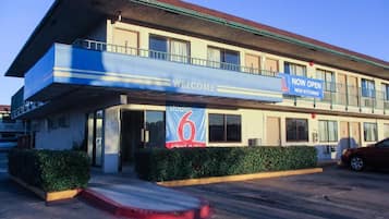A hotel with a 'Welcome' sign, a 'Now Open' sign, and a number '6' sign.