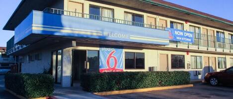 A hotel with a 'Welcome' sign, a 'Now Open' sign, and a number '6' sign.