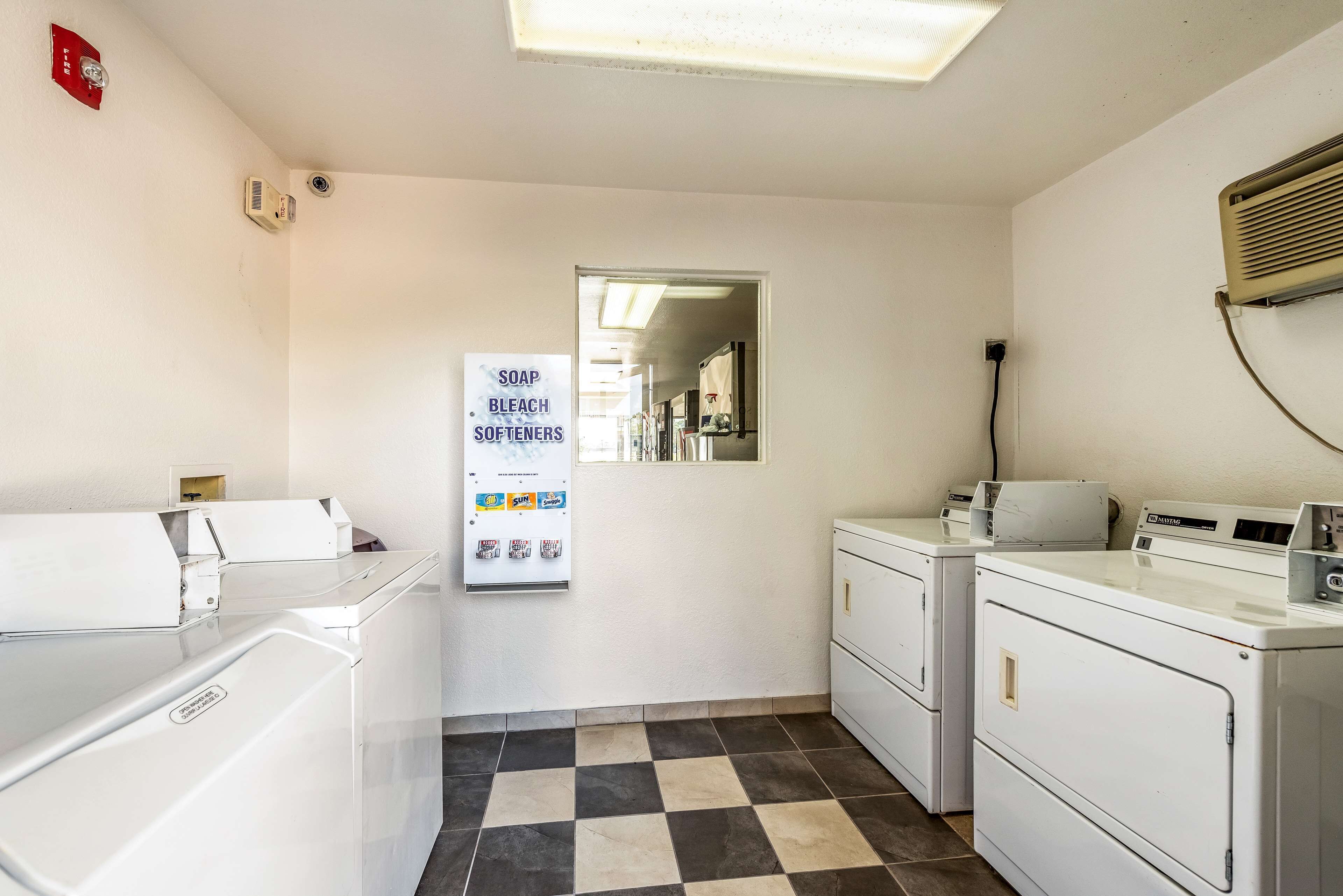 A laundry room with washers and dryers, a sign listing soap and bleach, and a mirror on the wall.