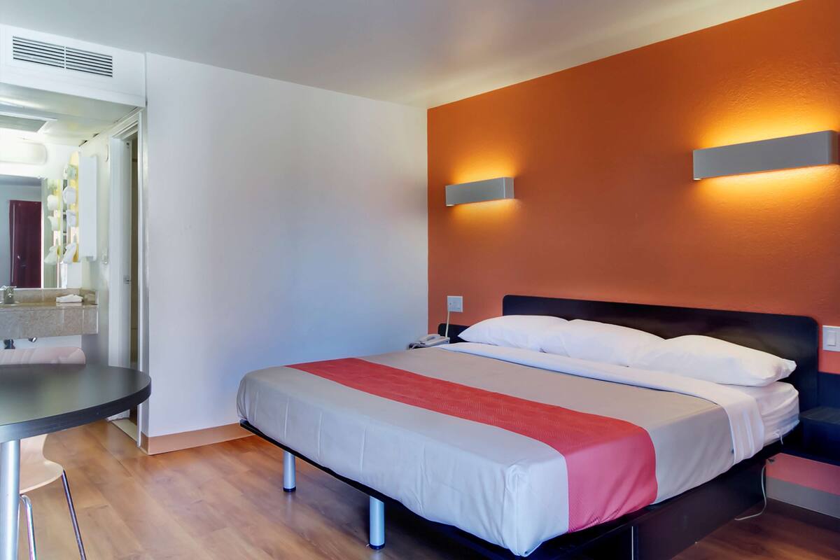 Une chambre d’hôtel avec un lit, une table de chevet et un miroir.