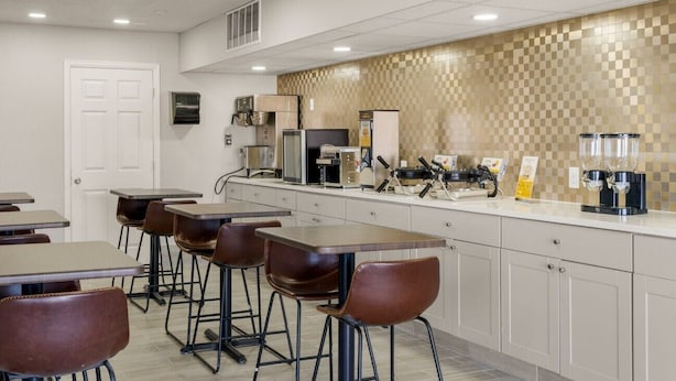 A modern kitchen with bar stools, a coffee machine, and a microwave. - Days Inn by Wyndham Wheat Ridge/Denver West (Wheat Ridge)