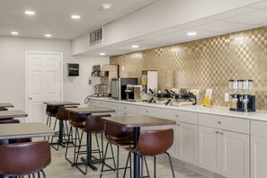 A modern kitchen with bar stools, a coffee machine, and a microwave.