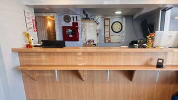 A reception desk with a clock, a fire extinguisher, and a Dell laptop.