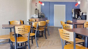 Un restaurant amb caires i taules de fusta, una zona de cuina i una paret d'accent blau.