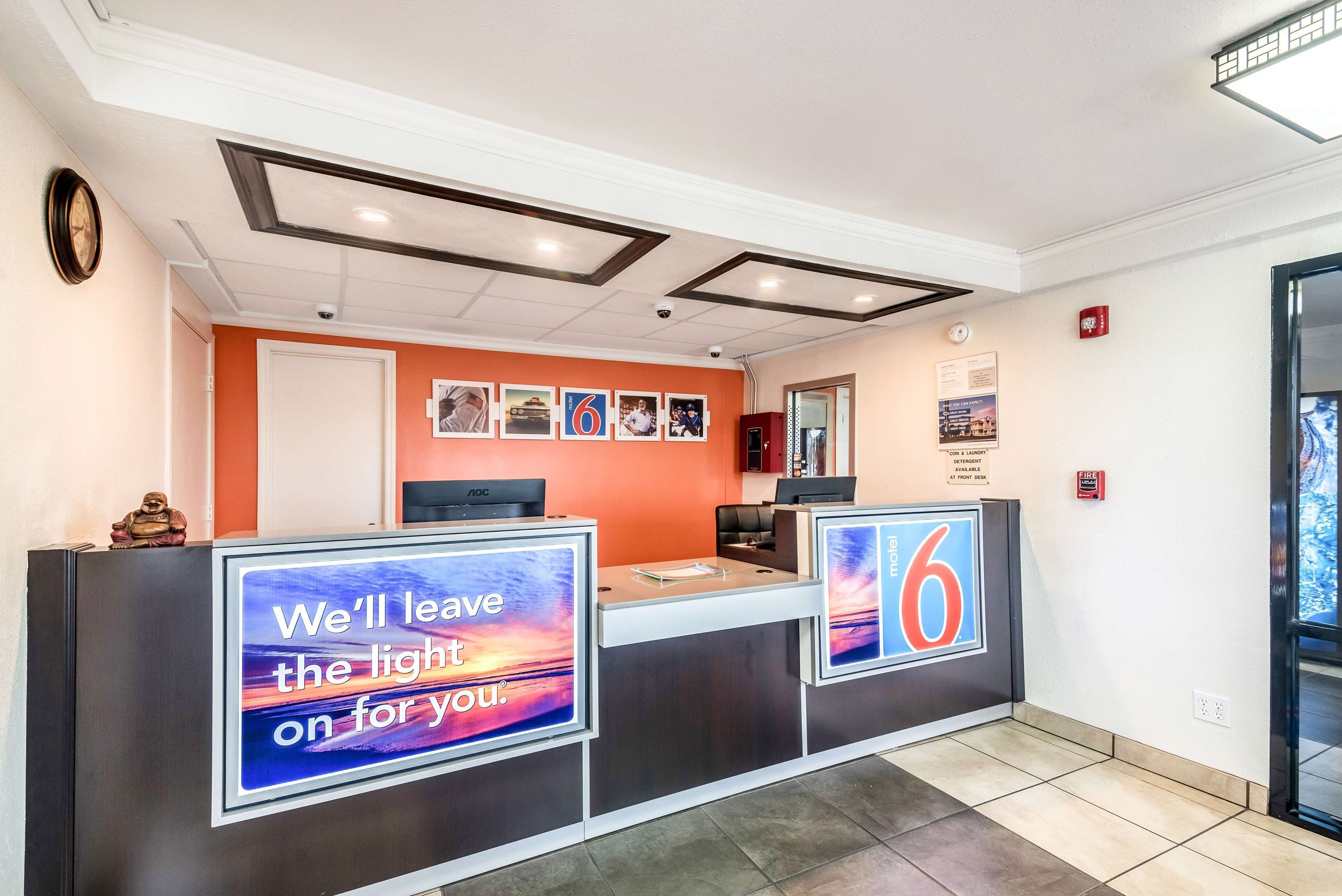 A hotel reception area with a modern design, featuring a reception desk, a clock, and a number '6' sign.