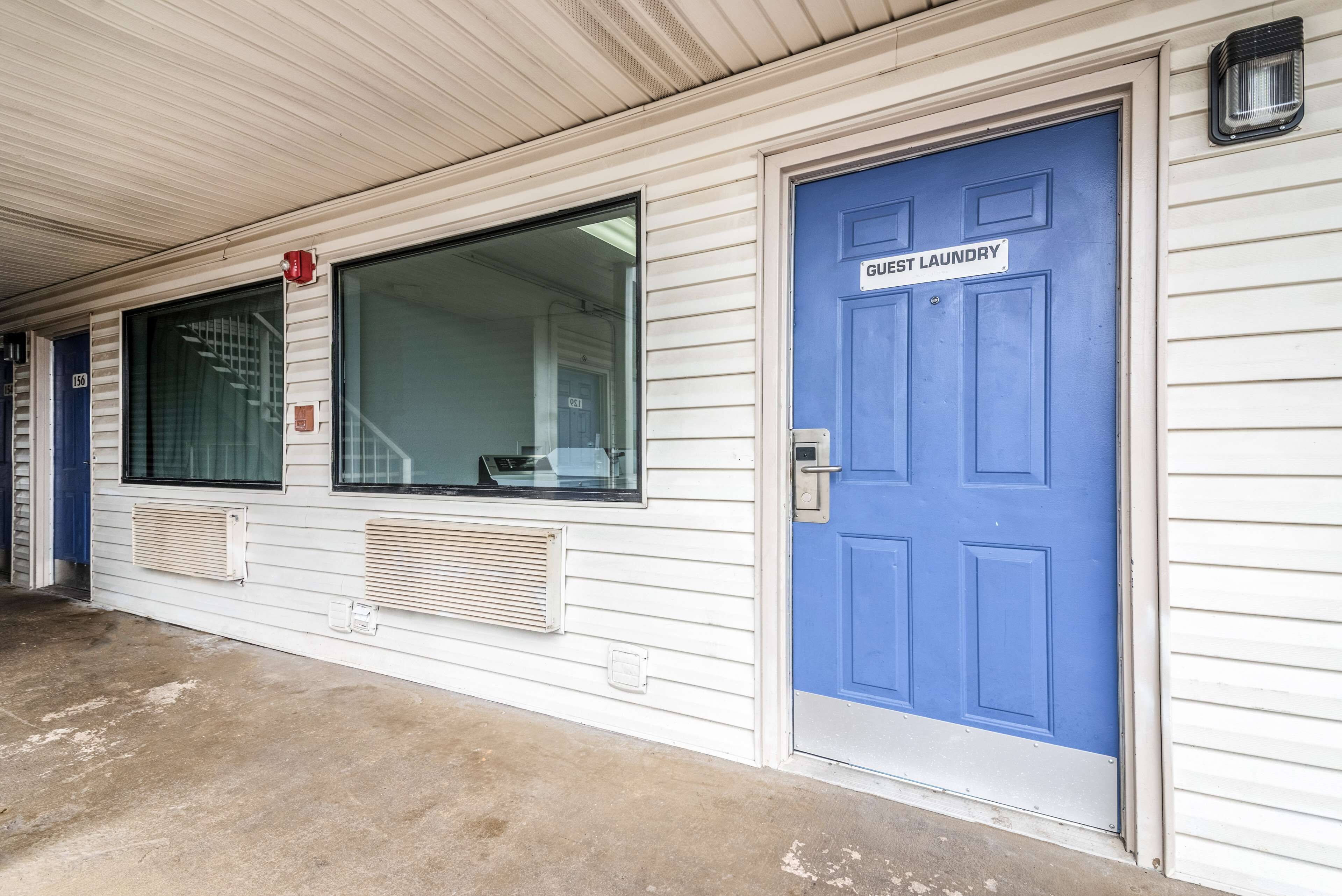A building with a blue door labeled "Guest Laundry" and a window with blinds.