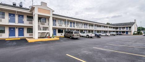 A motel with multiple rooms, a parking lot, and a few vehicles parked.