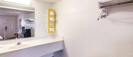 A bathroom with a white sink, a mirror, and a towel rack.