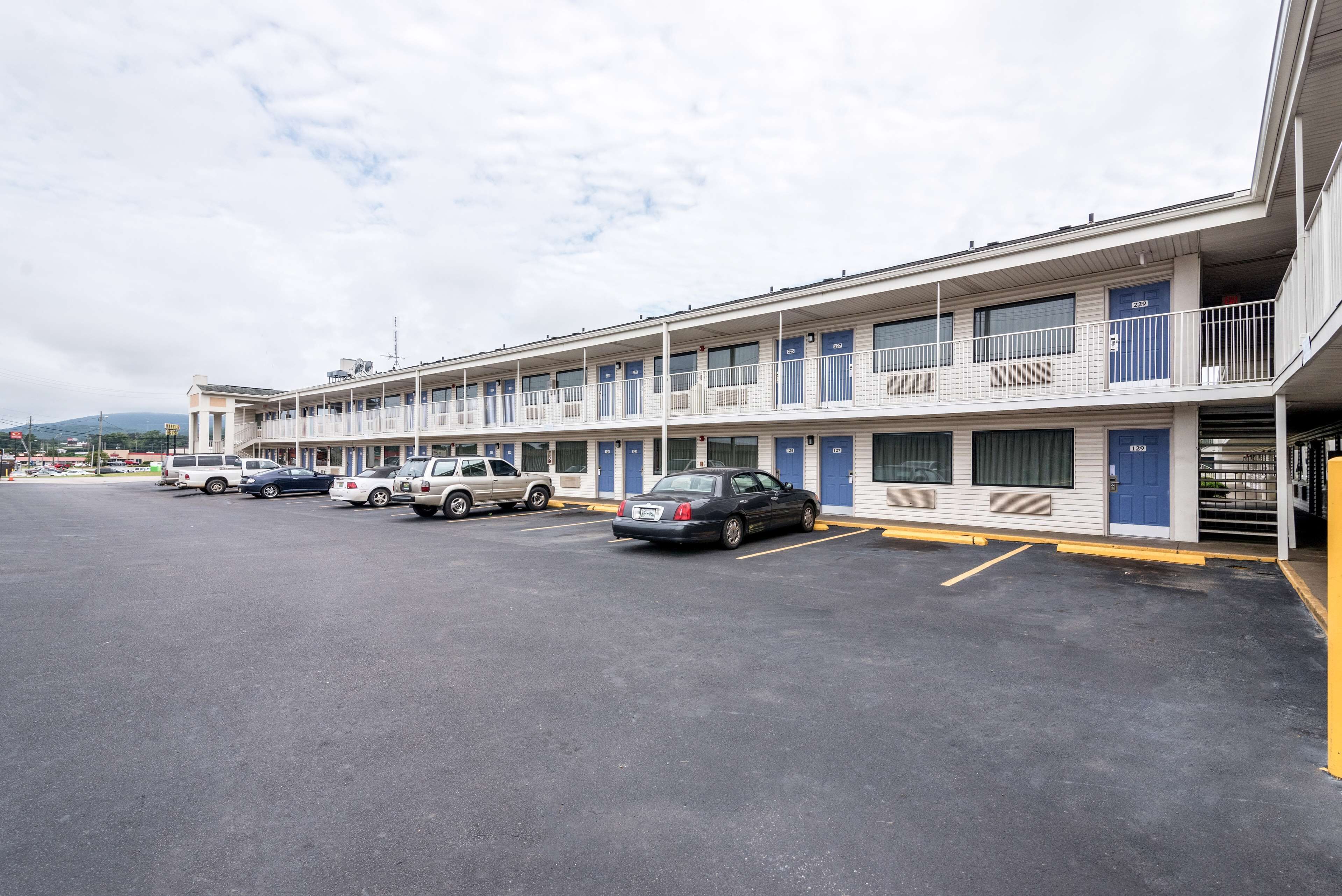 A motel with multiple rooms, a parking lot, and a few cars parked.