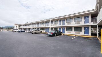 A motel with multiple rooms, a parking lot, and a few cars parked.