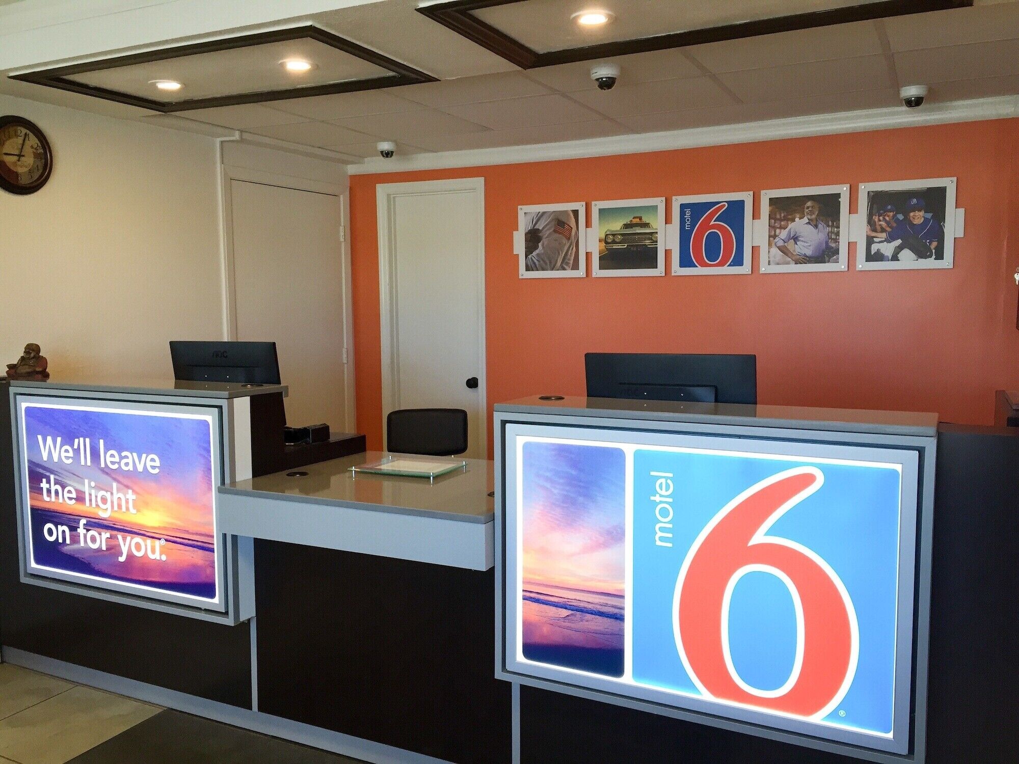 A motel reception desk with a digital sign displaying 'We'll leave the light on for you.'