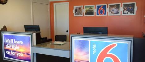 A motel reception desk with a digital sign displaying 'We'll leave the light on for you.'