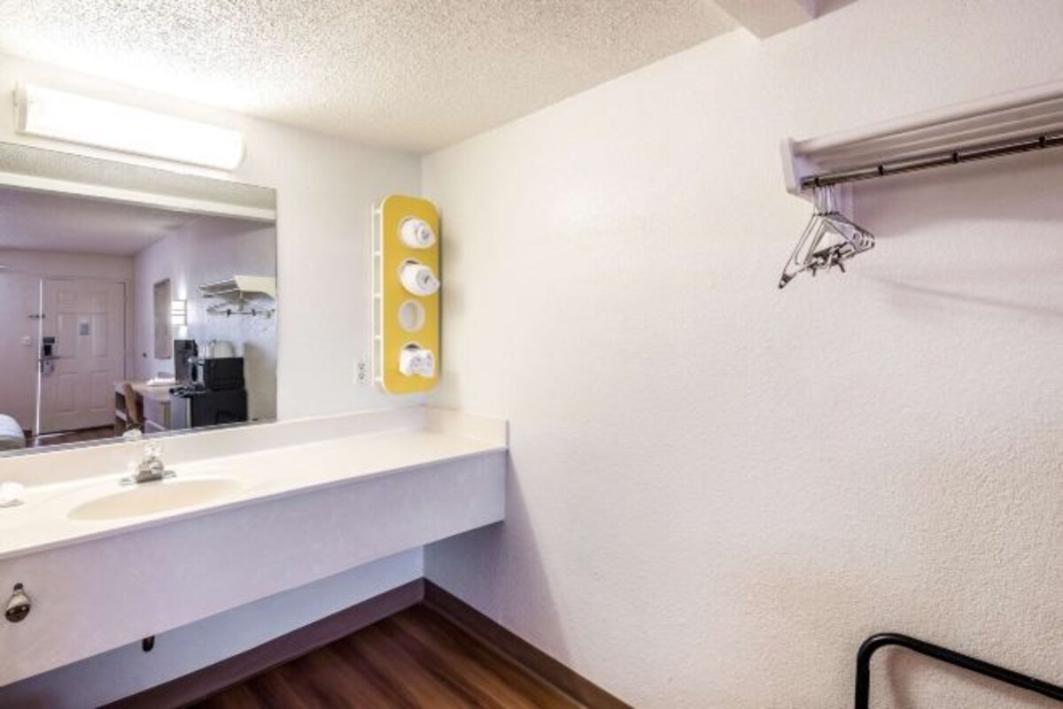 A bathroom with a white sink, mirror, and towel rack.