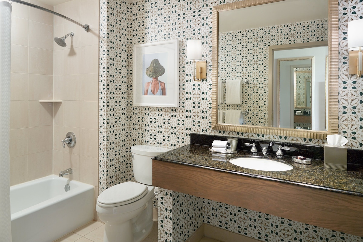Une salle de bain avec une baignoire, des toilettes, un lavabo et un grand miroir.